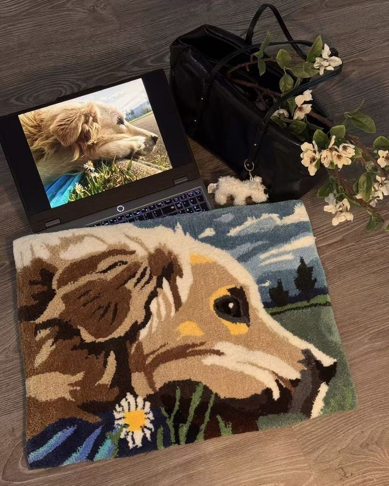 A rug with a dog portrait, next to the original photo open on a laptop.