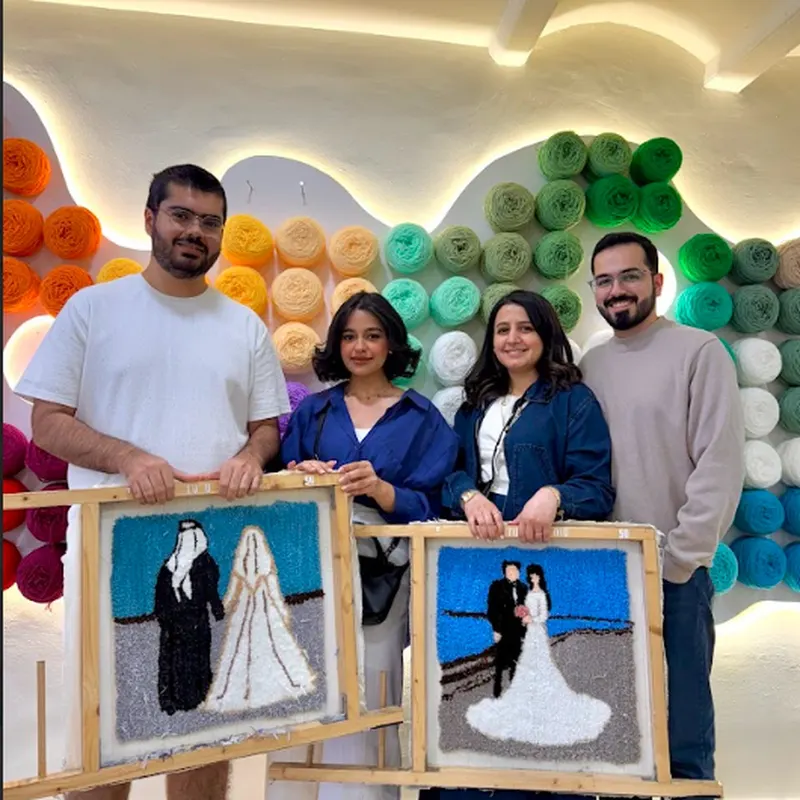 Grupo en el taller de tufting con la pared de hilos de colores