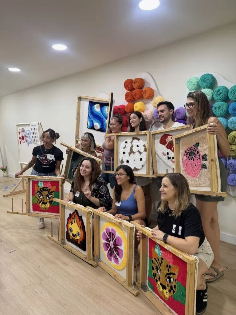 Coworkers holding their handmade tufted rugs after a creative team building activity in Barcelona